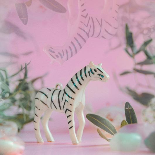 Un jouet à la forme d'un zèbre sur un fond rose avec des plantes.
